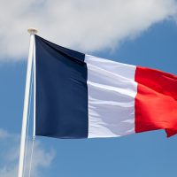 French flag against blue sky with clouds